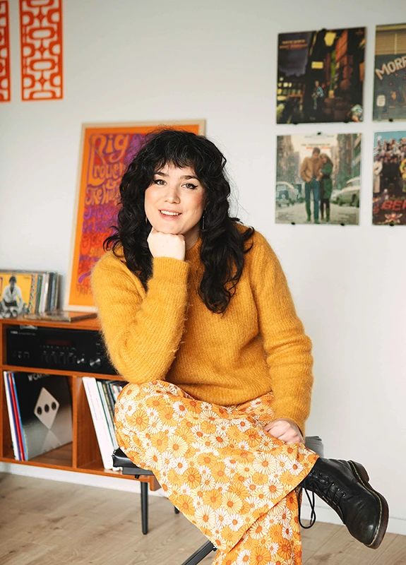 Roxane assise sur un tabouret dans son local de cours de chant